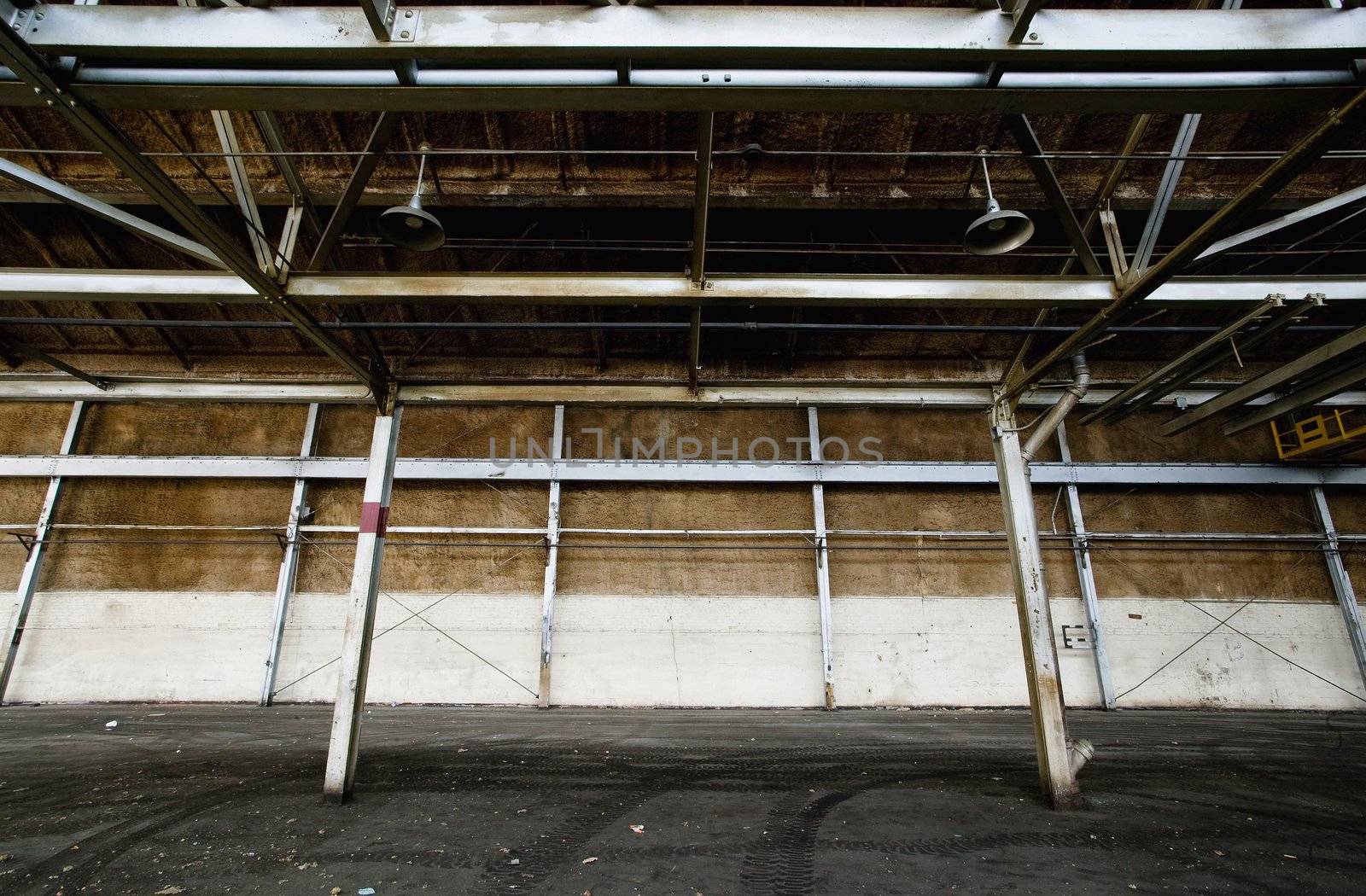 Interior of an empty and abandoned industrial building with exposed girders.