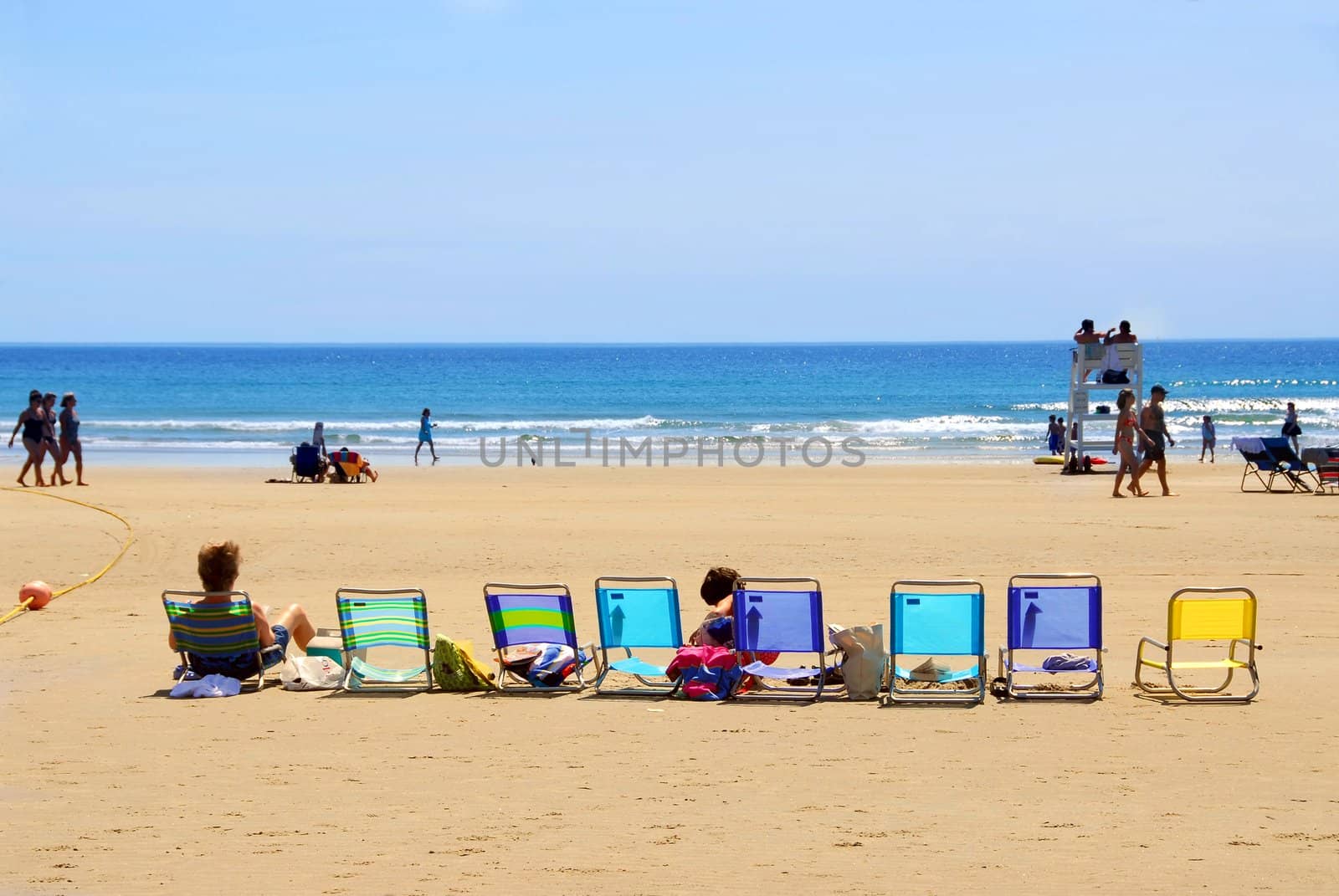 A row of colorful folding chairs on a sandy beach