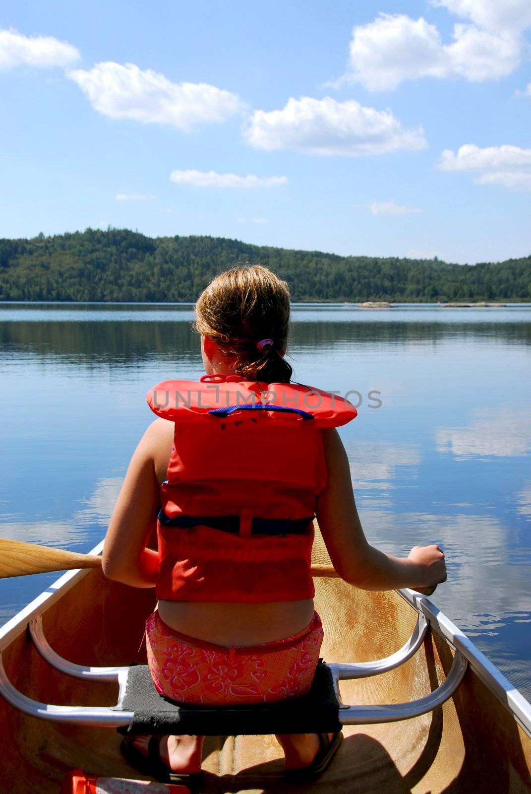 Child in canoe paddling on a scenic lake