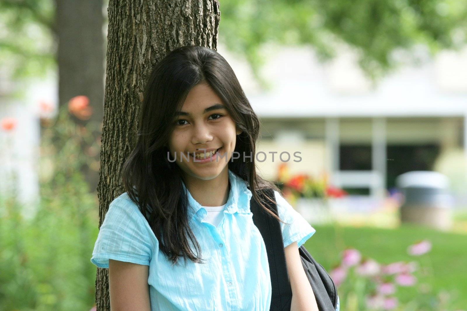 Young teen girl standing with backpack by tree by jarenwicklund