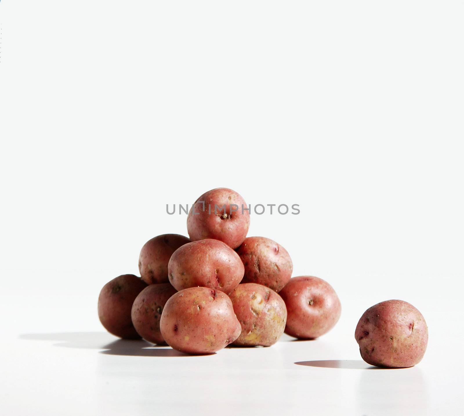 Pile of organic red potatos against a pure white background.