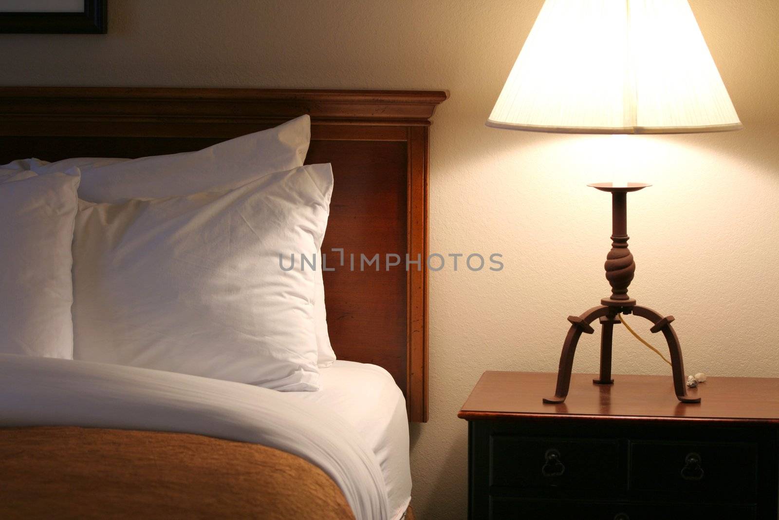 Comfortable and serene bedside lit by lamp light;