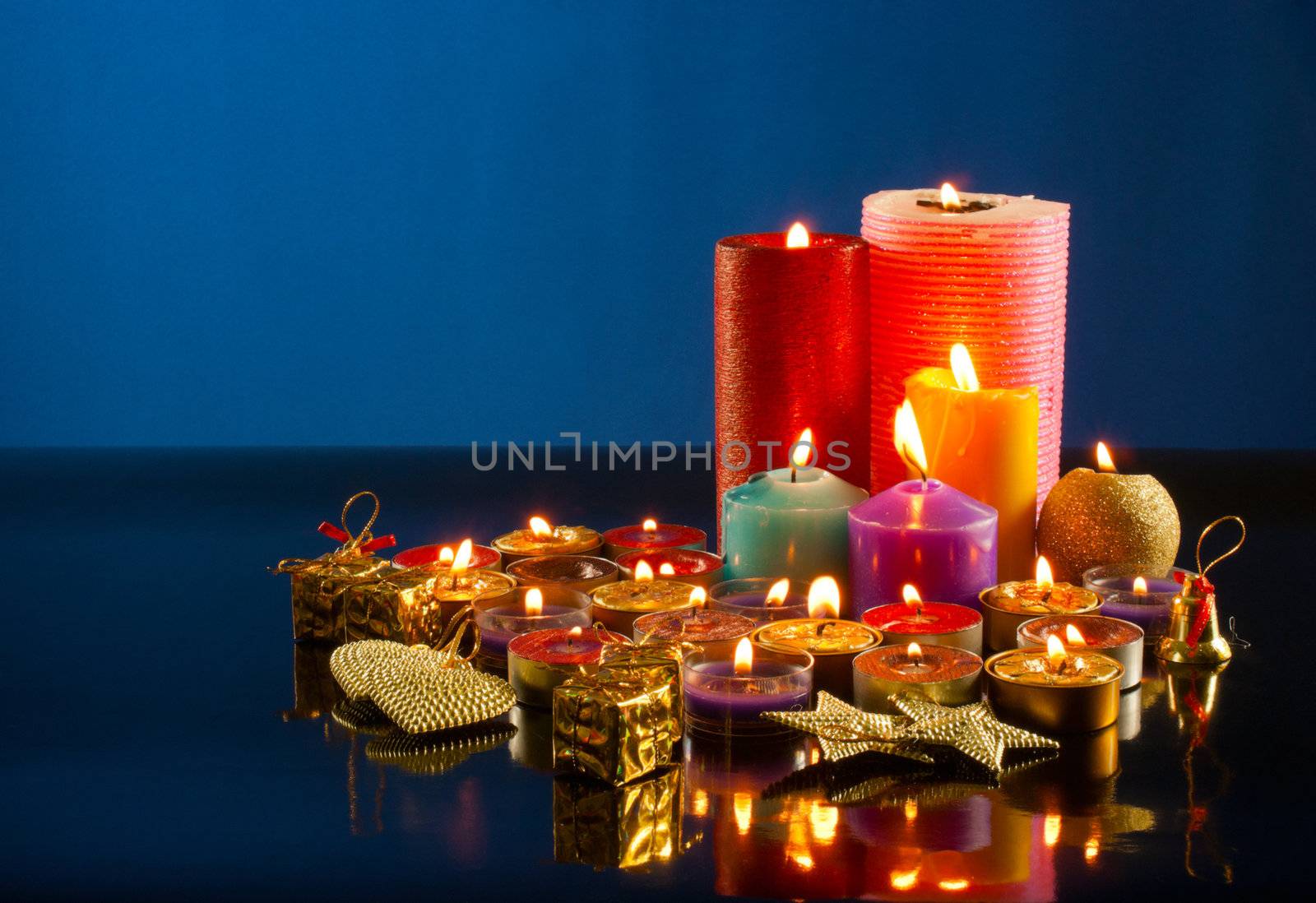 A lot of burning colorful candles against dark blue background