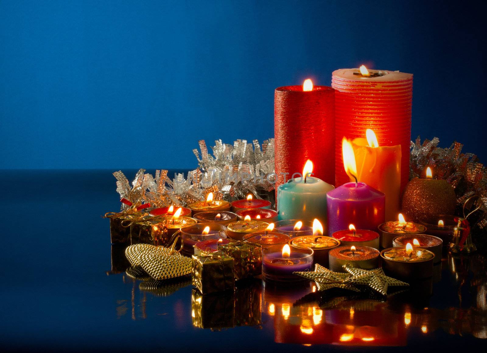 A lot of burning colorful candles against dark blue background