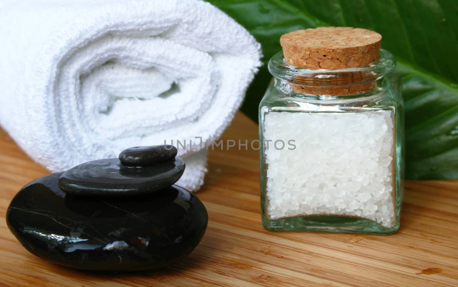 White bath towel, bottle of sea salt and black stones in spa composition

