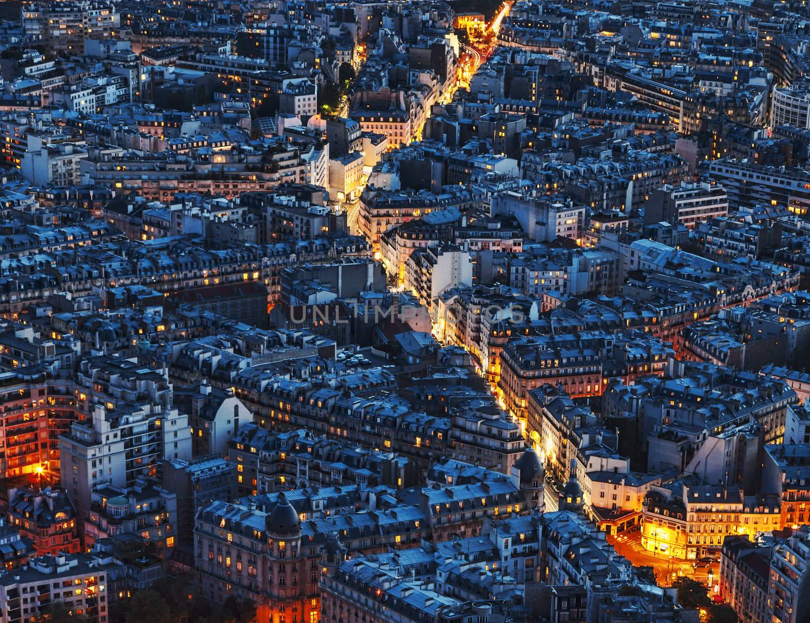 Aerial night view of an illuminated street between crowded buildings in Paris.