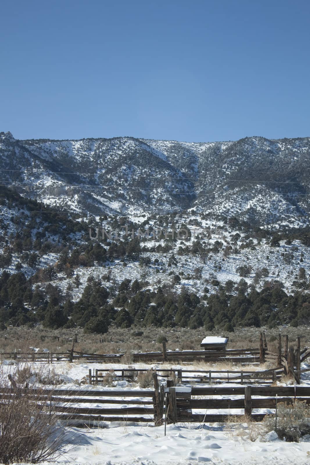 A high desert mountain range with snow on it.farm country