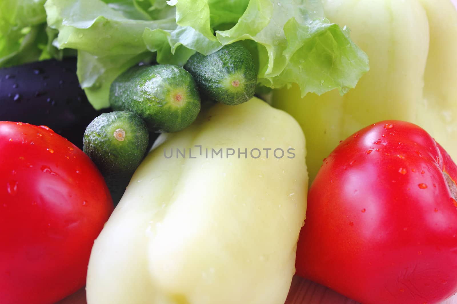 Fresh tomatoes, cucumbers, pepper, eggplant and lettuce on wood table.