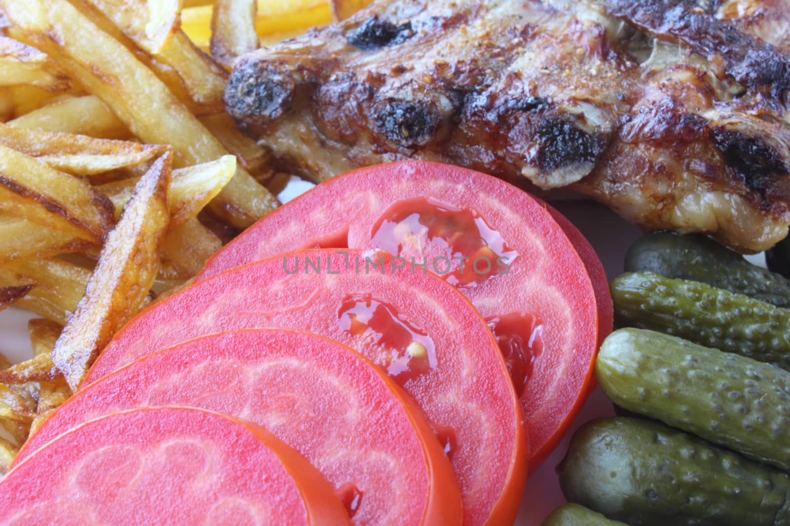 Grilled pork ribs with roasted potatoes, fresh tomato and pickle cucumbers