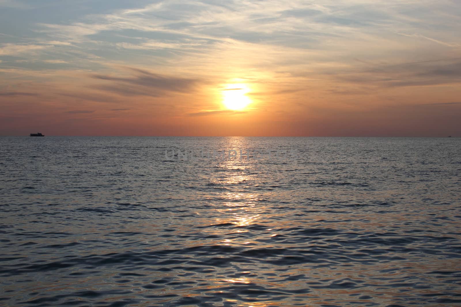 Sunset on sea with ship on horizon