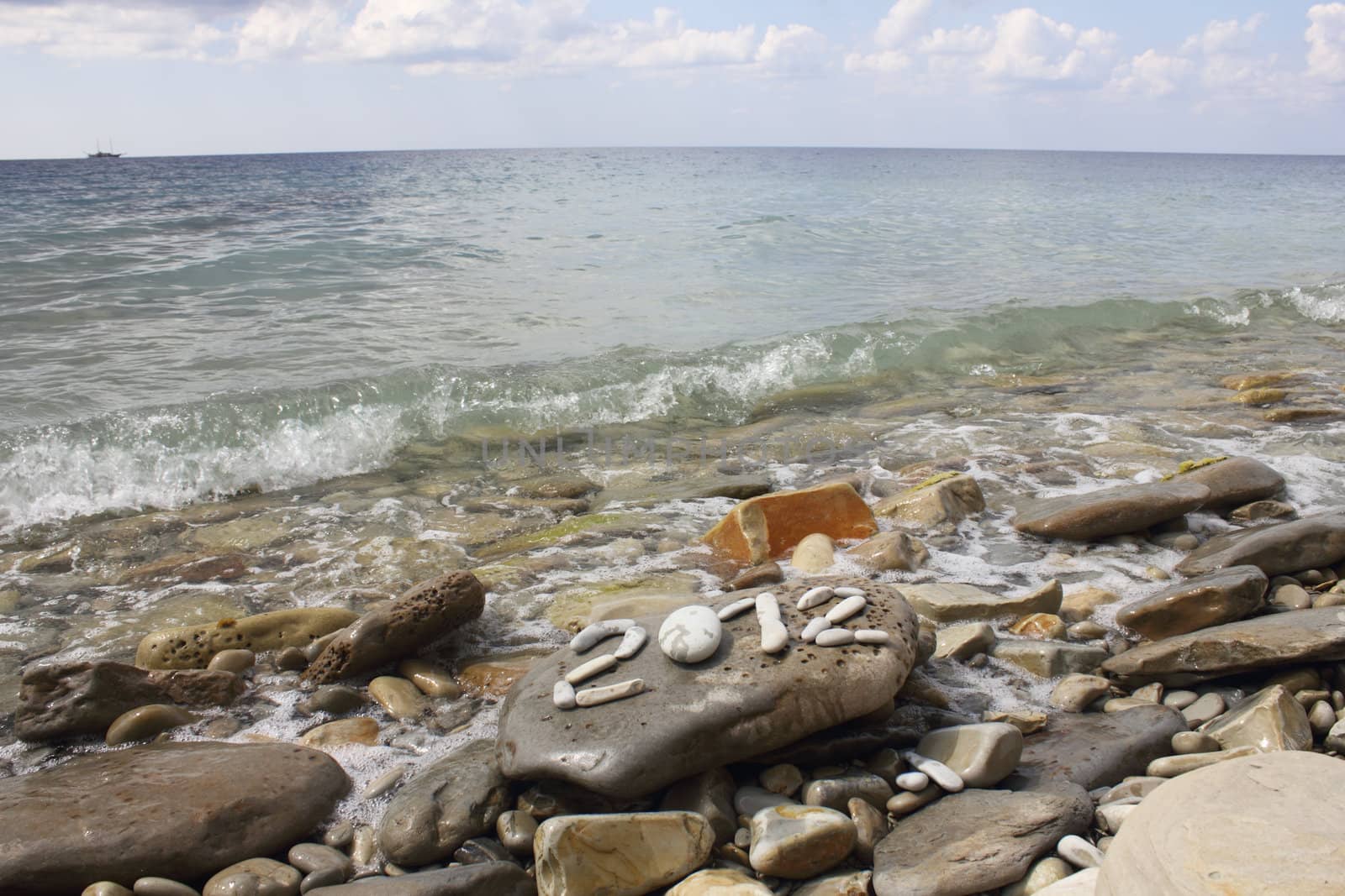 Digits 2012 on stone sea coast with ship on horizon