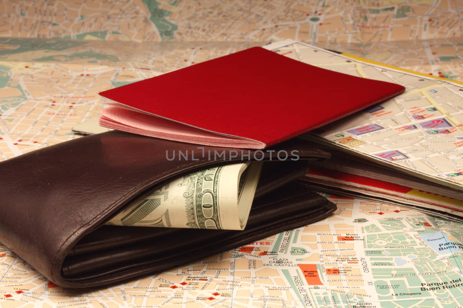 Wallet, passport and stack of maps on city map.