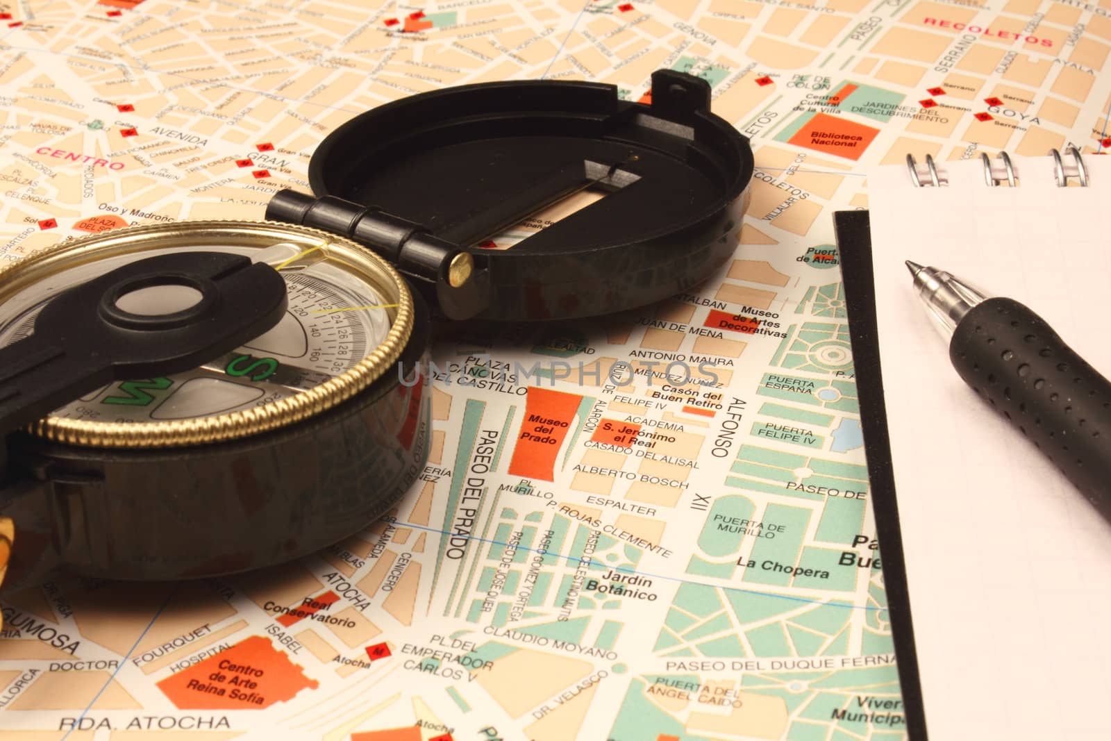 Compass, notebook and pen on city map.