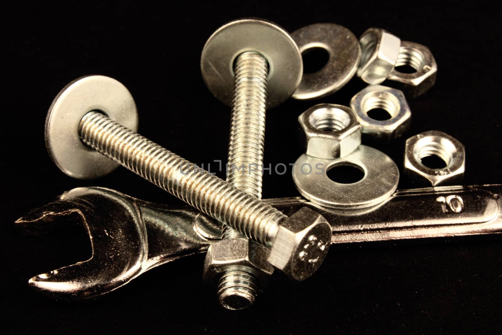 Wrench, bolts, nuts and washers on black background