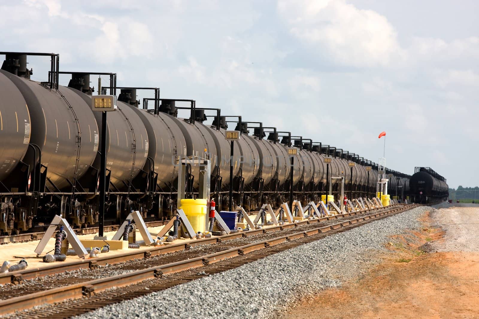 Long lines of railroad oil tanker cars stretch off into the distance down the train tracks waiting to be unloaded.