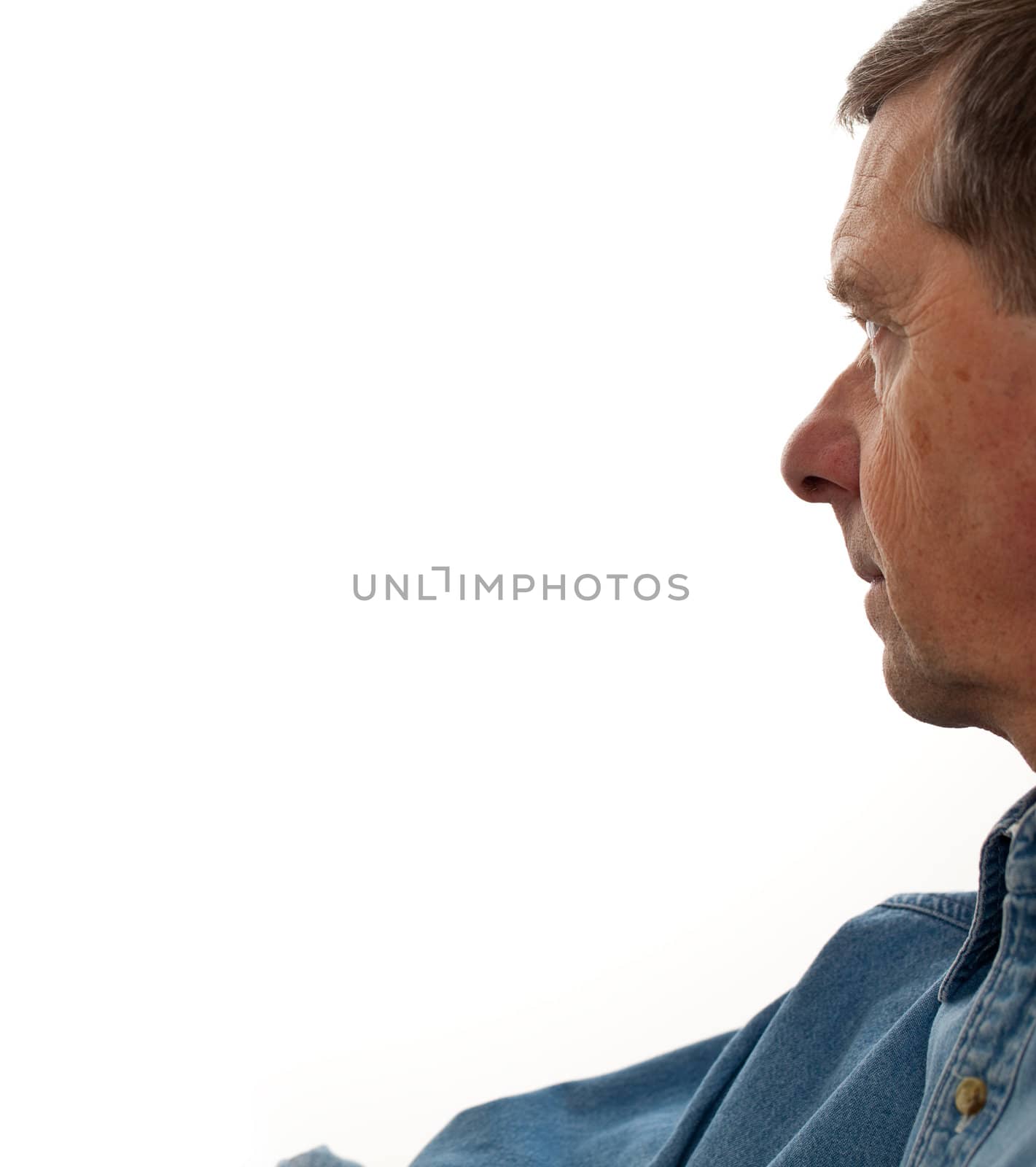 Profile of a middle aged man reaching for something to the left of the page and staring into the distance