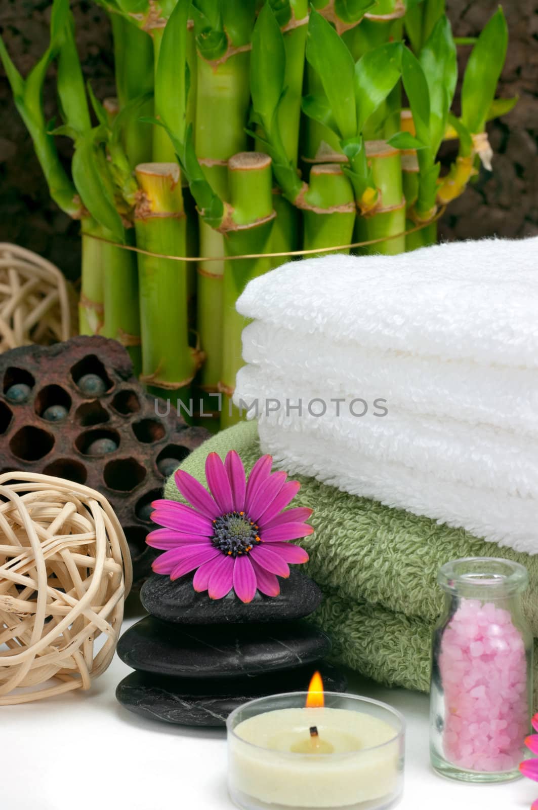 Spa scene with bamboo, towels, aromatic candles, bath salt, pebbles and daisies