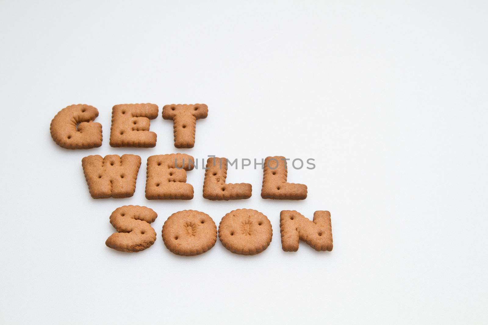 Get well soon wording made by brown biscuits on white surface landscape orientation