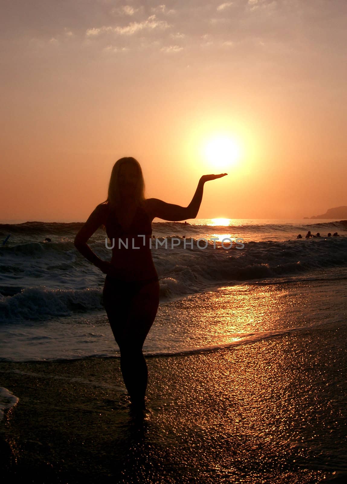 silhouette woman on beach holding sun in hand at sunset 