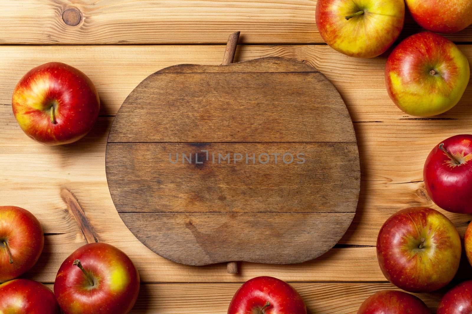 Fresh apples on wooden table. Composition with fruits and cutting board with apple shape. Copy space