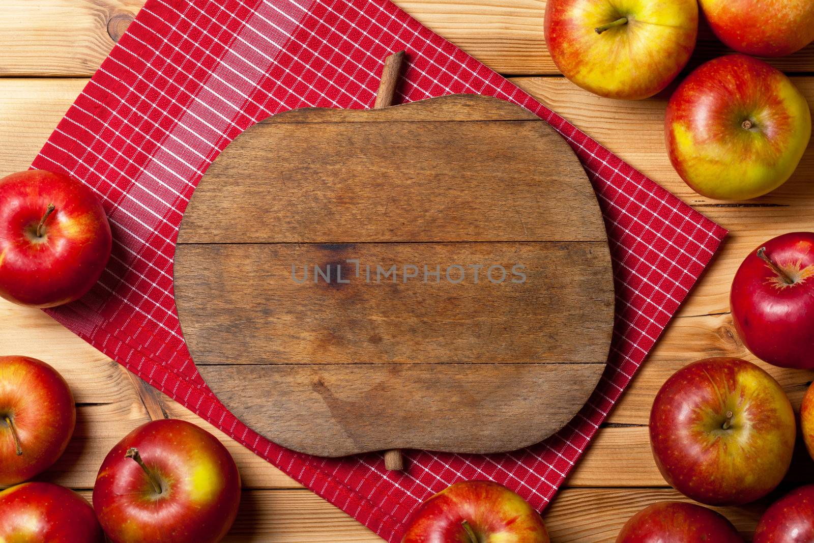 Fresh apples on wooden background. Composition with fruits and cutting board with apple shape. Copy space