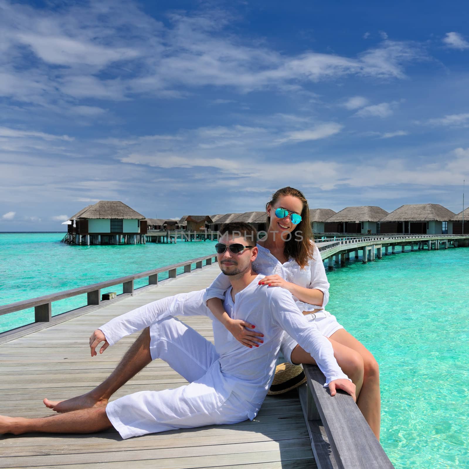 Couple on a tropical beach jetty at Maldives