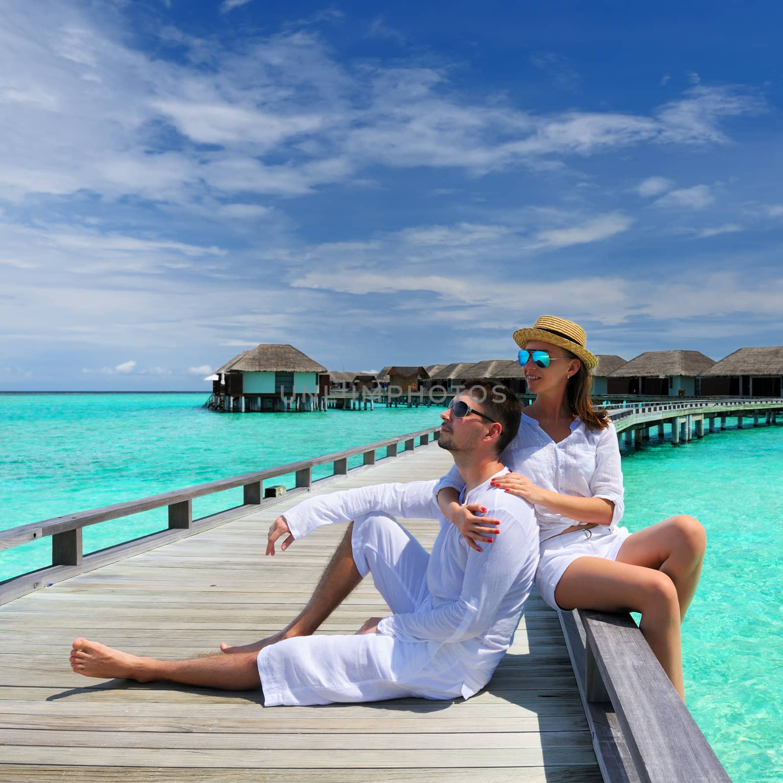 Couple on a tropical beach jetty at Maldives