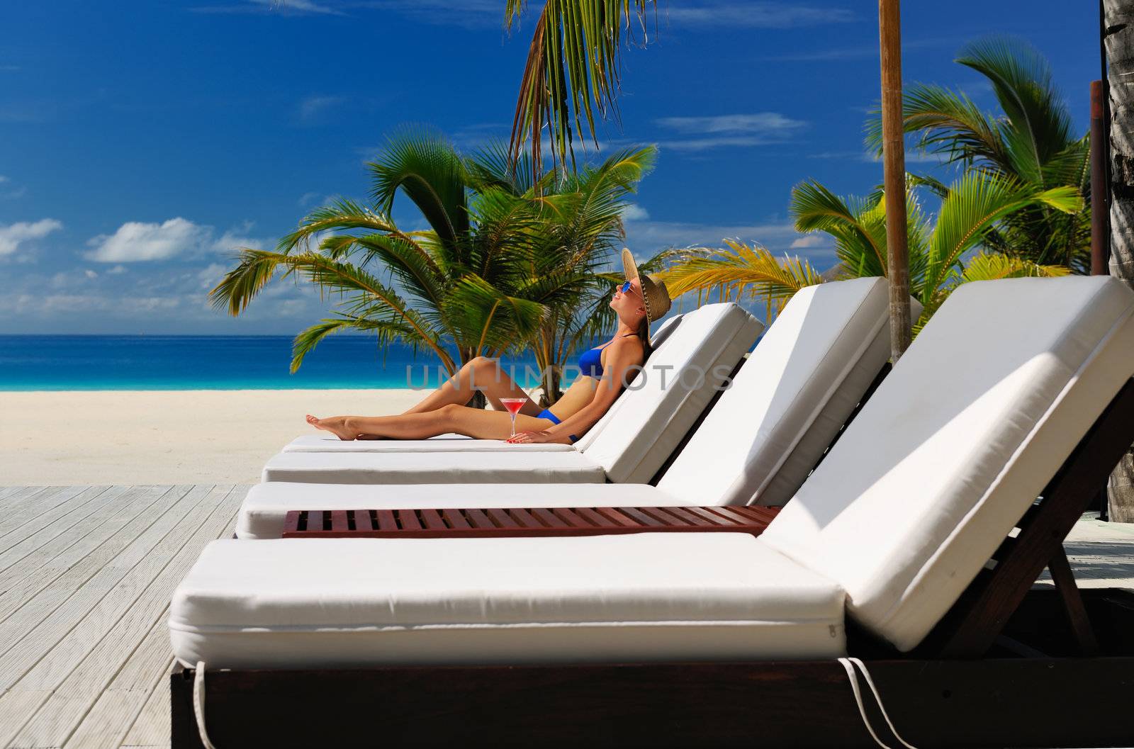 Woman in hat relaxing at the poolside with cosmopolitan cocktail