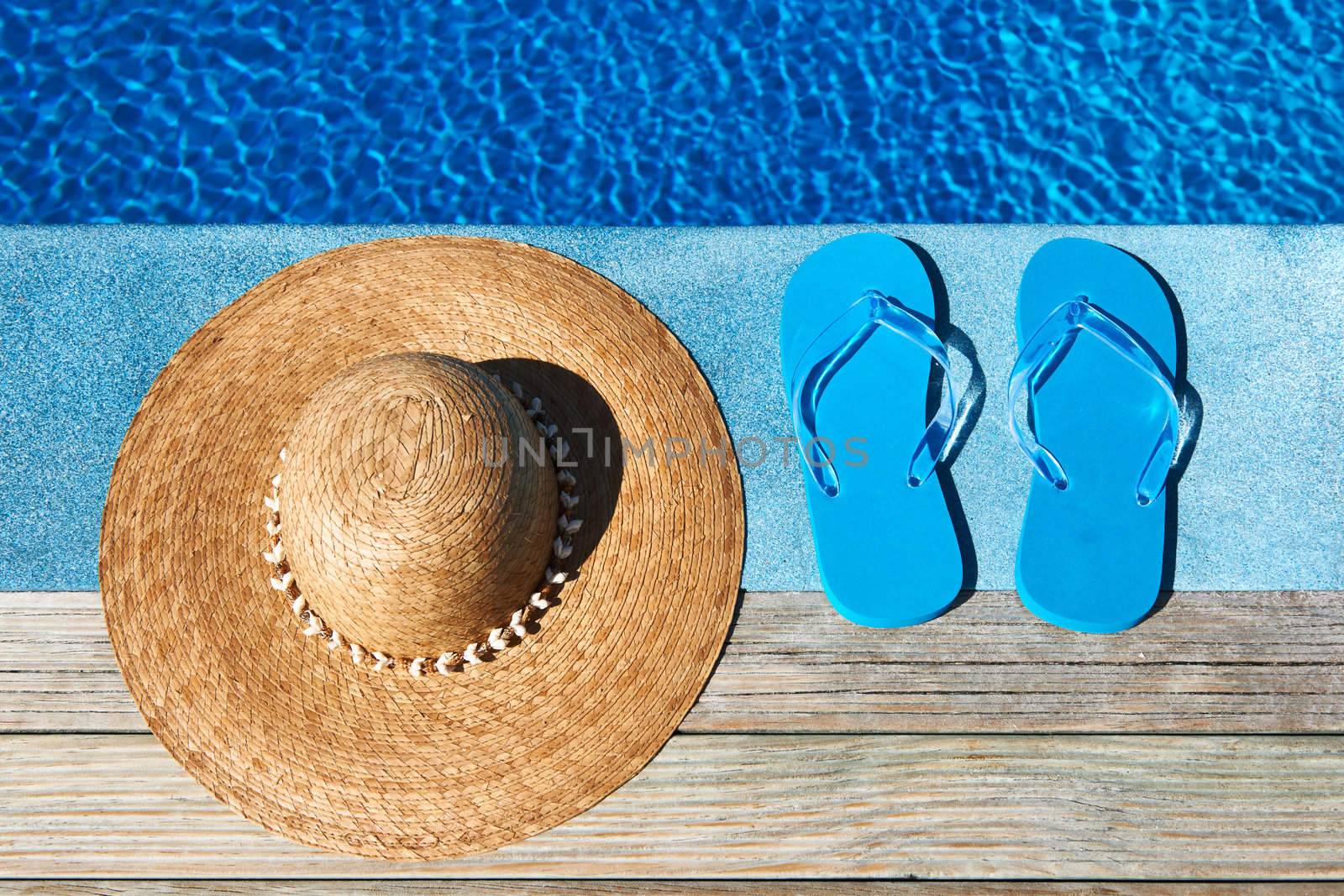 Blue slippers and hat by a swimming pool 