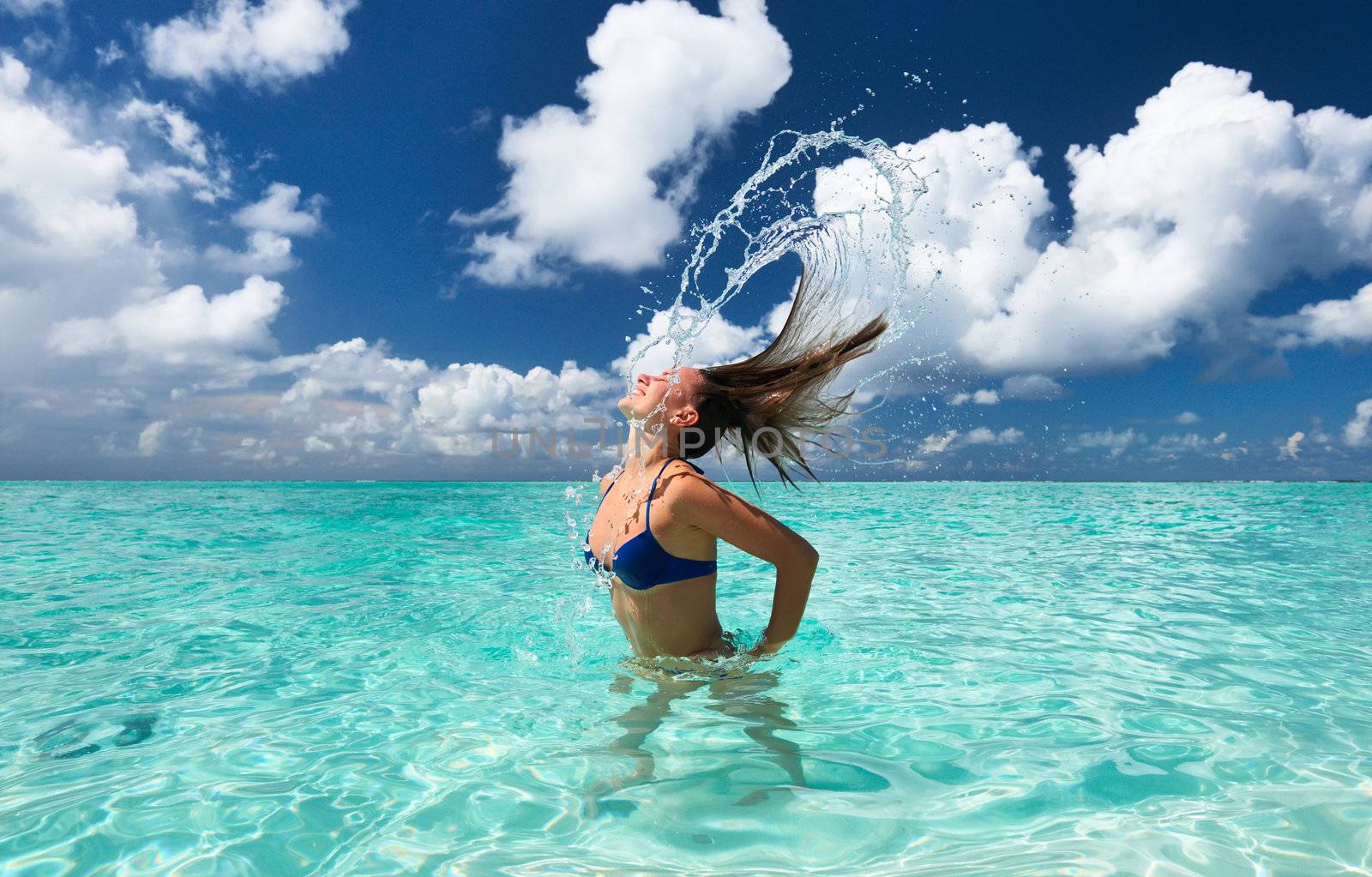 Woman splashing water with her hair in the ocean