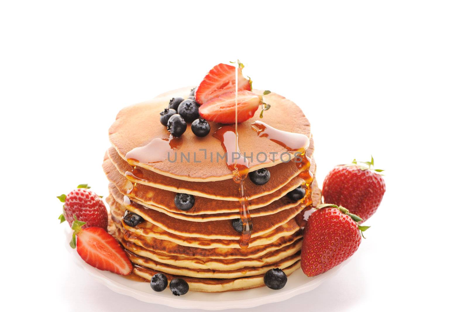 Delicious freshly prepared pancakes with strawberry and blueberries isolated on white