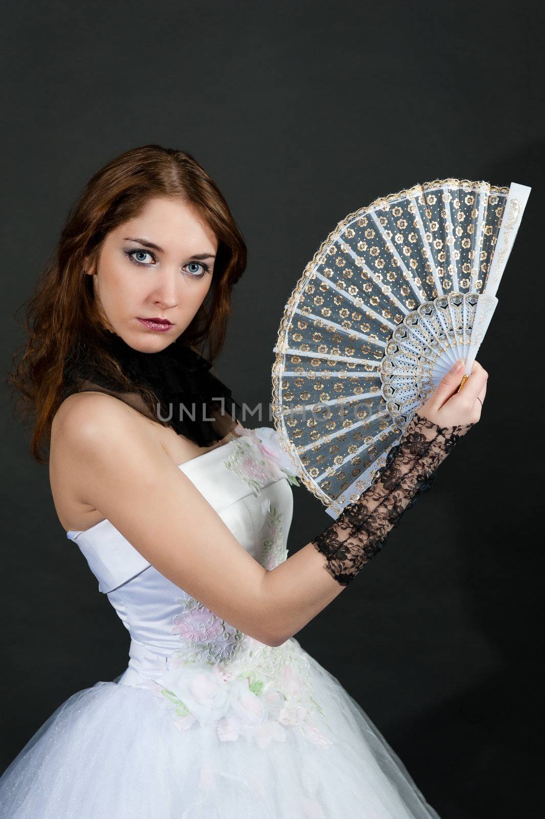 Girl with fan in white dress on black background
