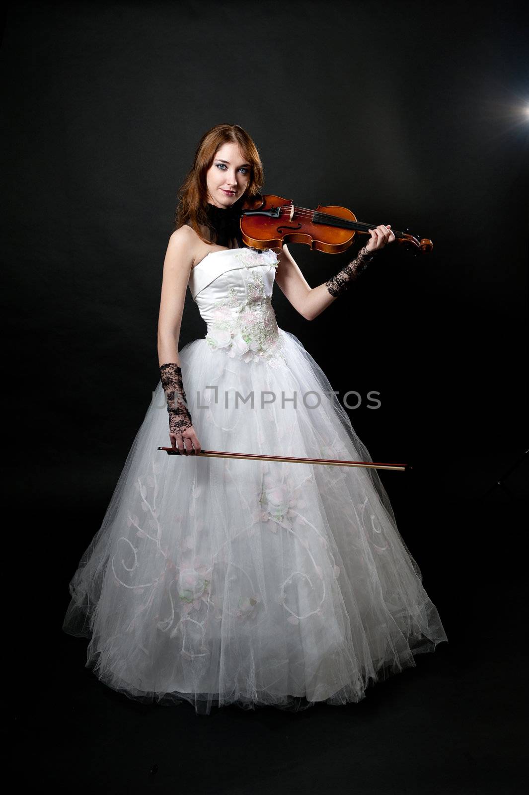 Girl in white dress with violin on black background