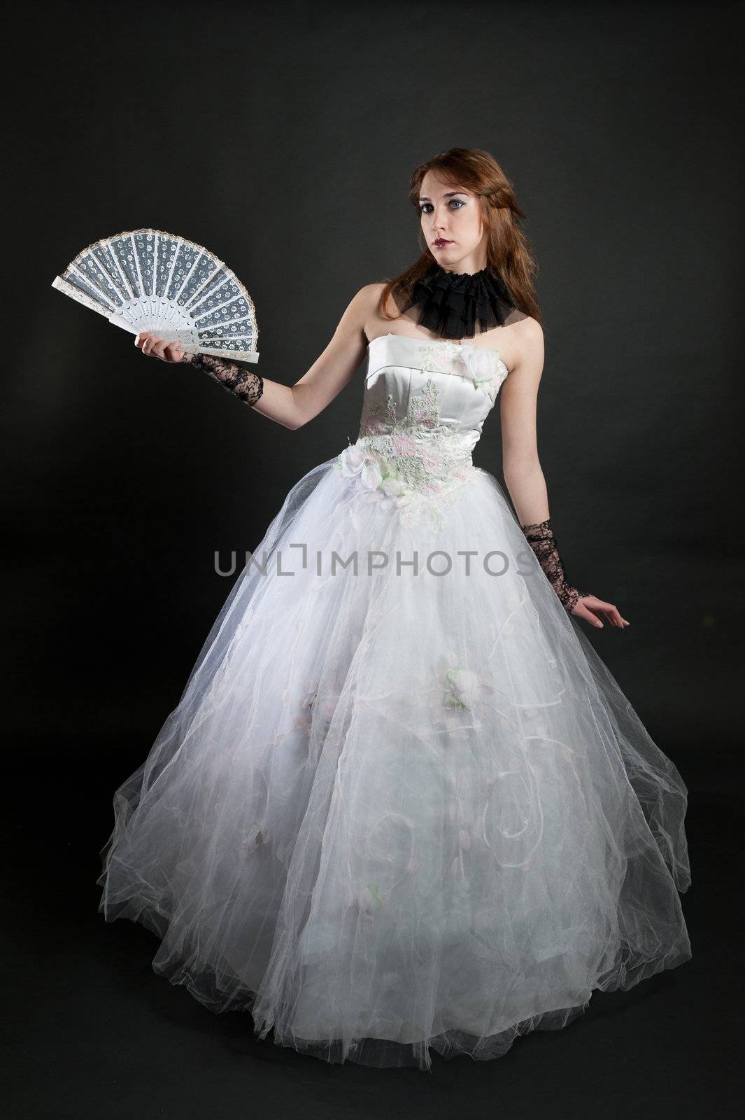 Girl with fan in white dress on black background