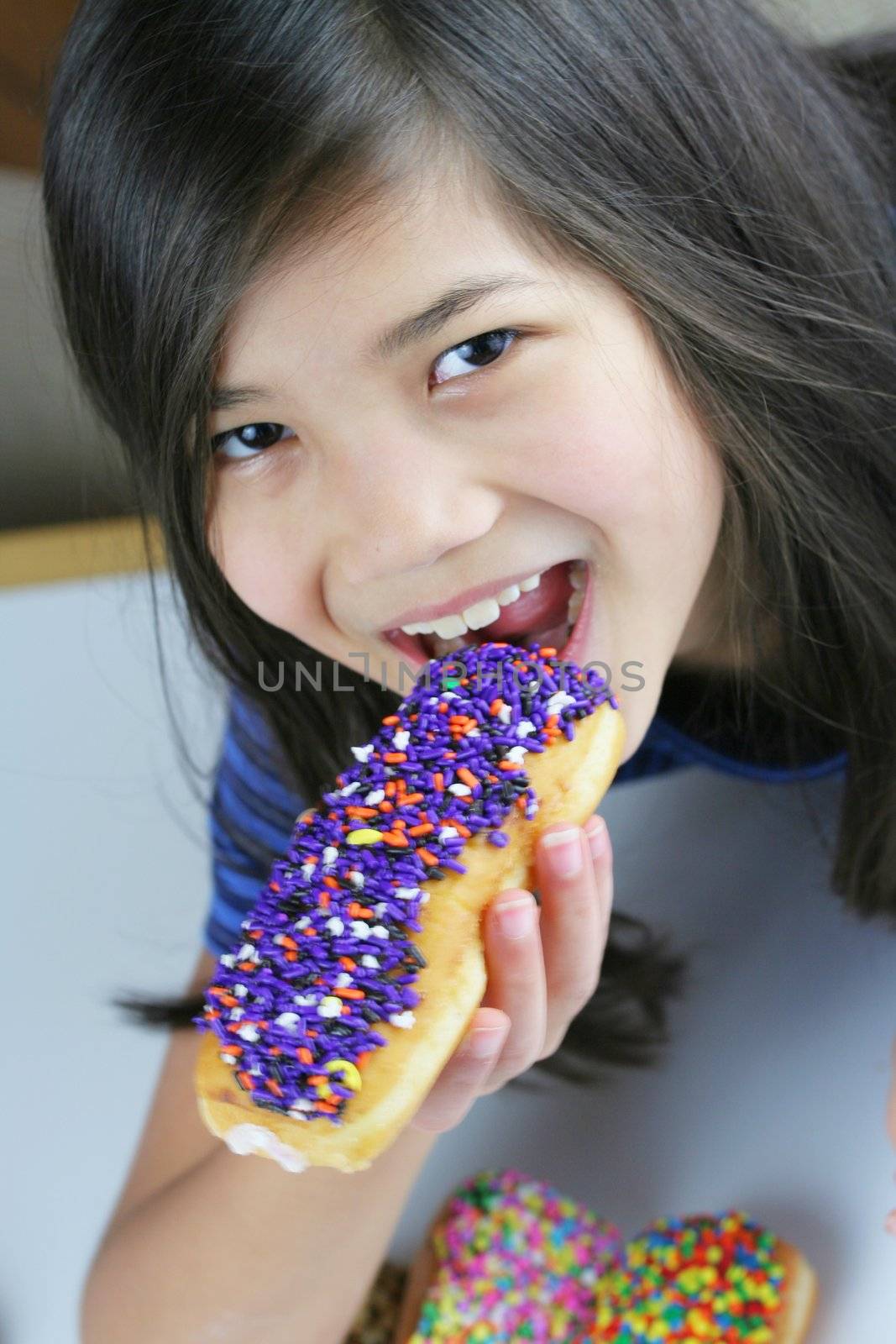 Girl holding colorful donut, ready to eat; by jarenwicklund