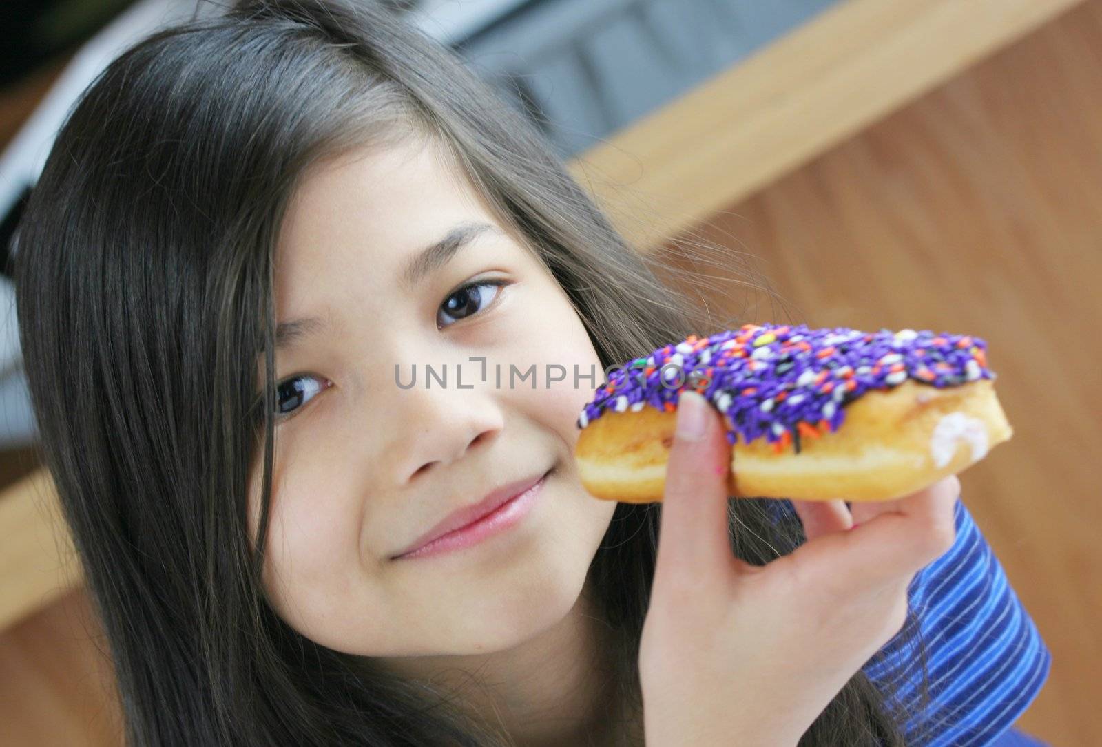 Girl holding colorful donut, ready to eat;