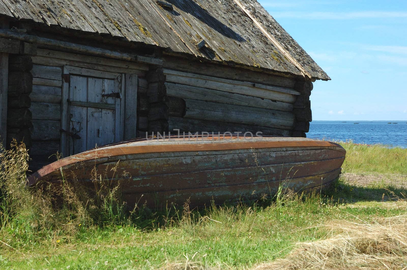 Lake in summer, old reverse wooden fishing boat near the shed