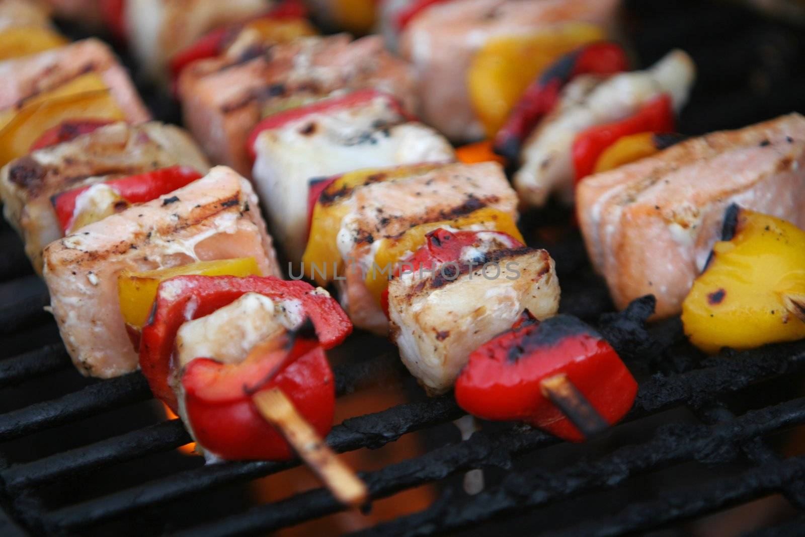 fresh fish on grilling sticks, salmon and halibut with red and yellow pepper being barbecued, very delicious looking