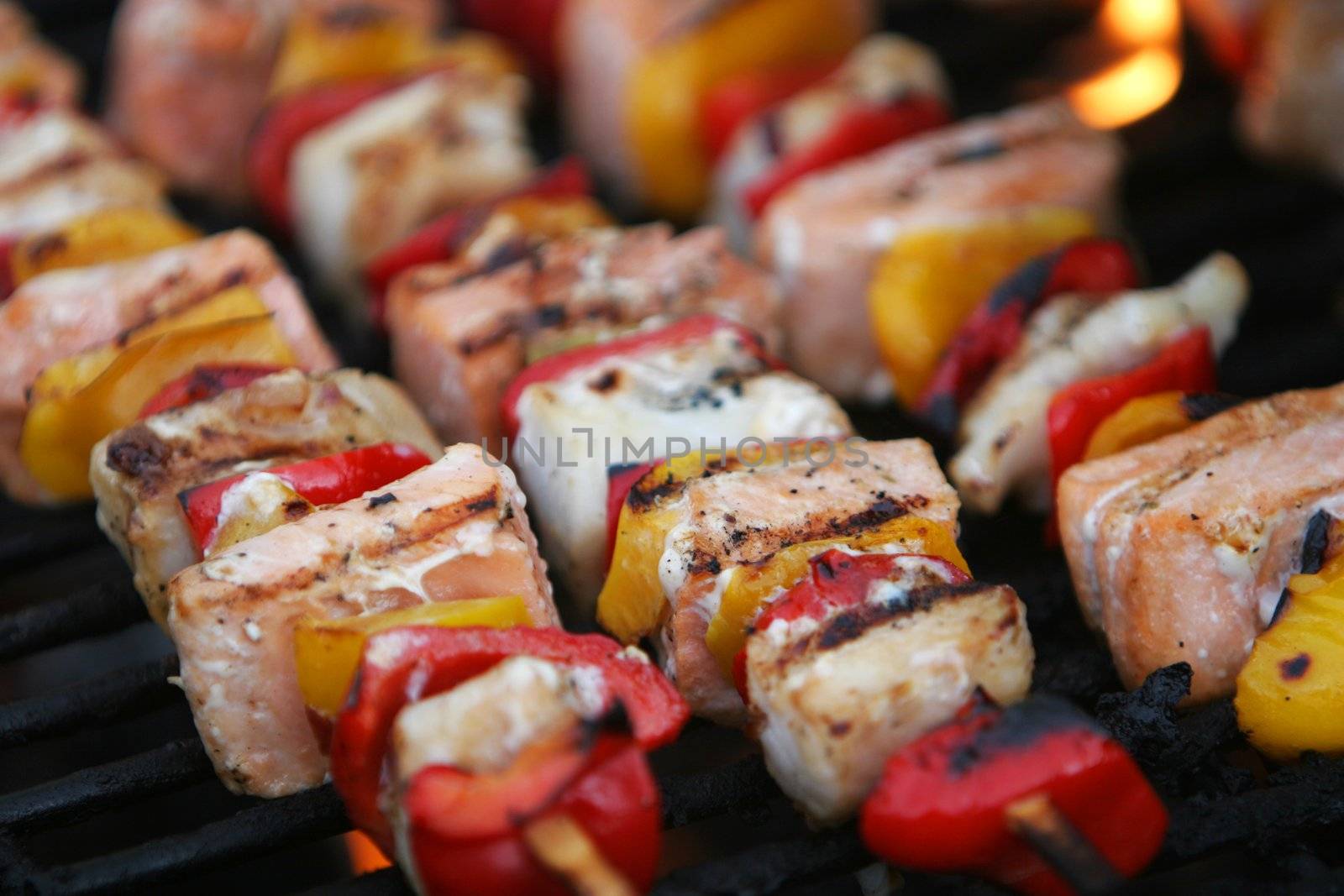 fresh fish on grilling sticks, salmon and halibut with red and yellow pepper being barbecued, very delicious looking