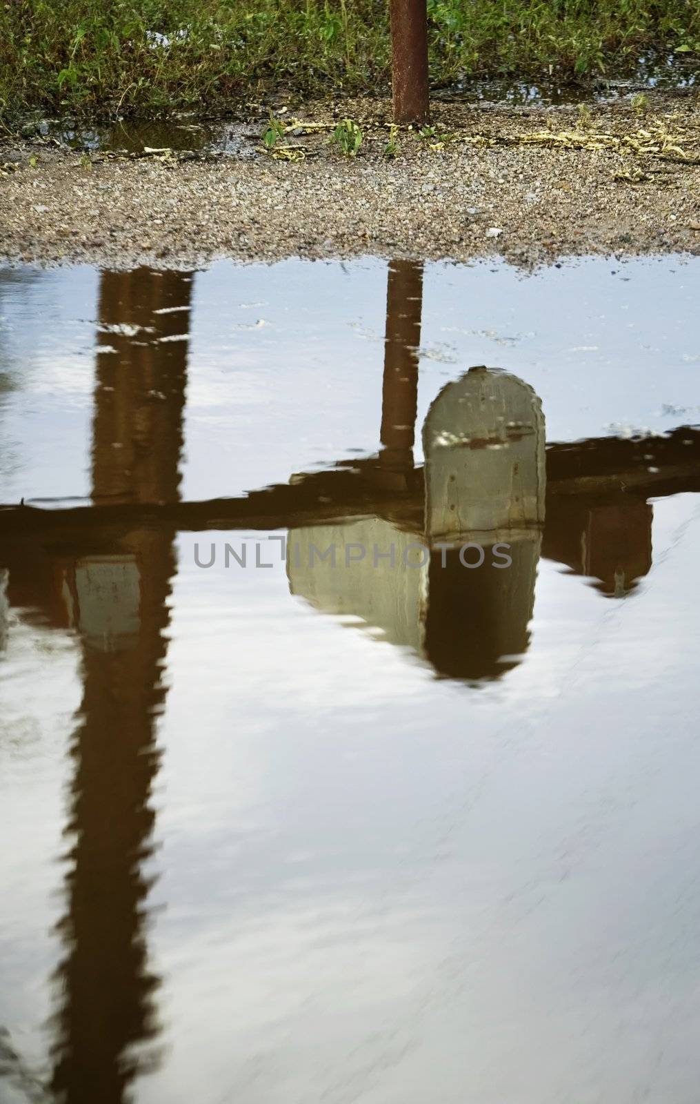 Open rural mailbox reflected in a puddle after a rain storm.