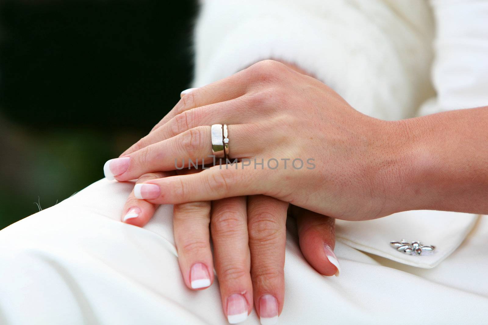 A wedding,bride sitting with hands in lap, cropped shot with focus on hands and wedding ring