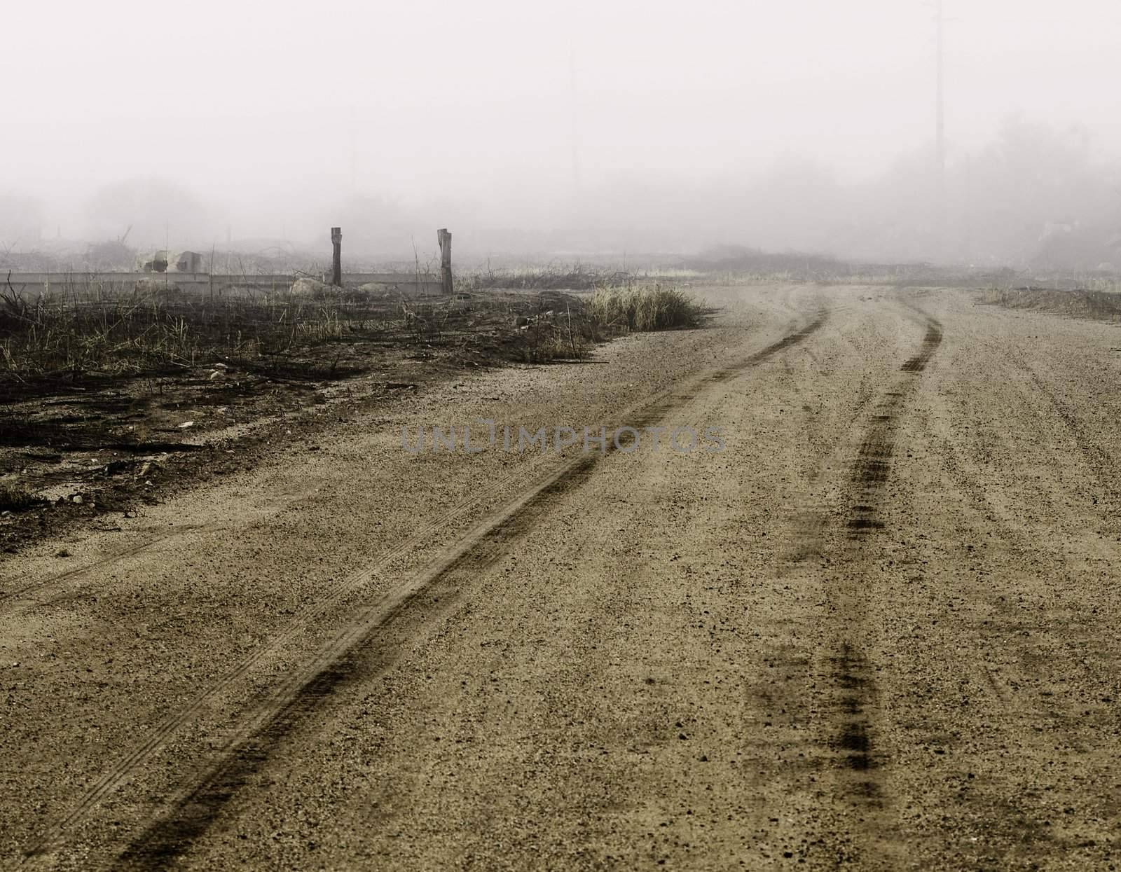 Tire tracks in dirt heading of into the distance on a foggy day.