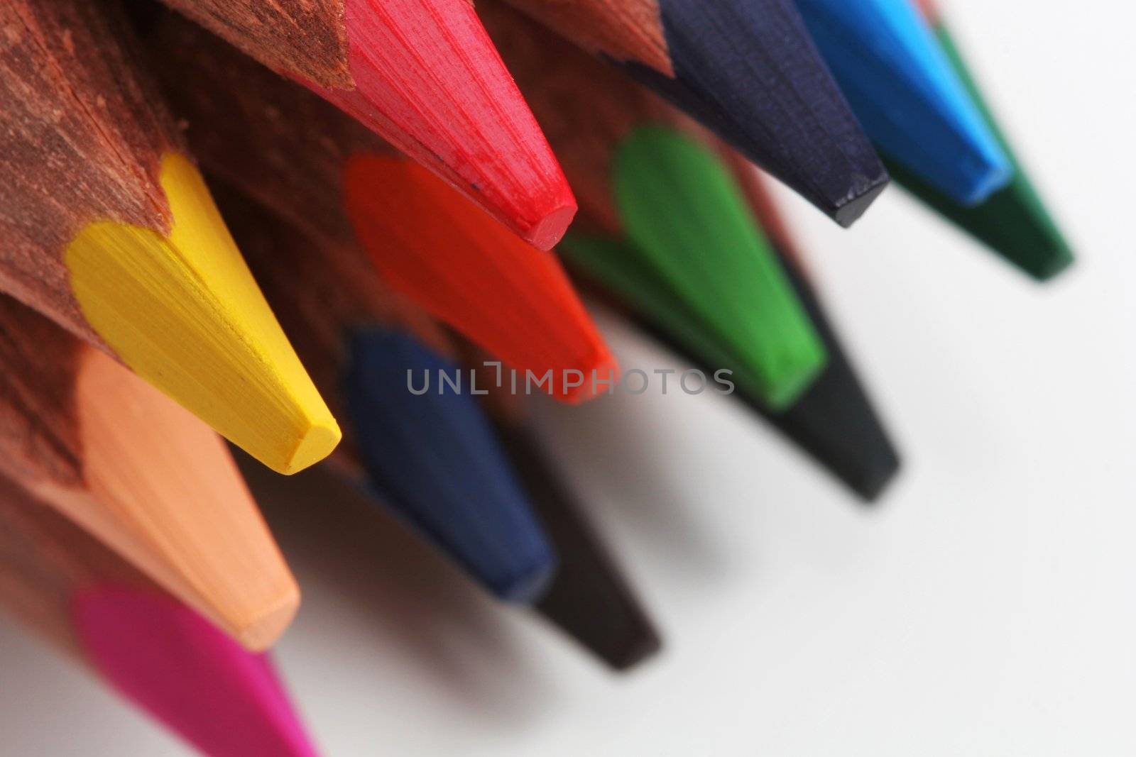 A macro shot of the front end of a group of colored pencils, isolated on white