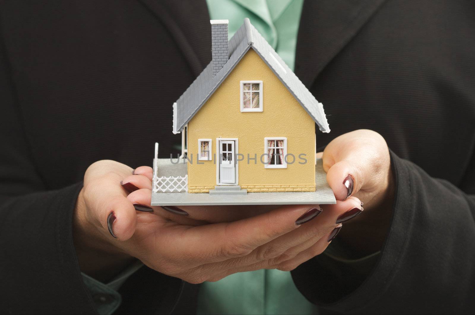 Female hands holding small house.