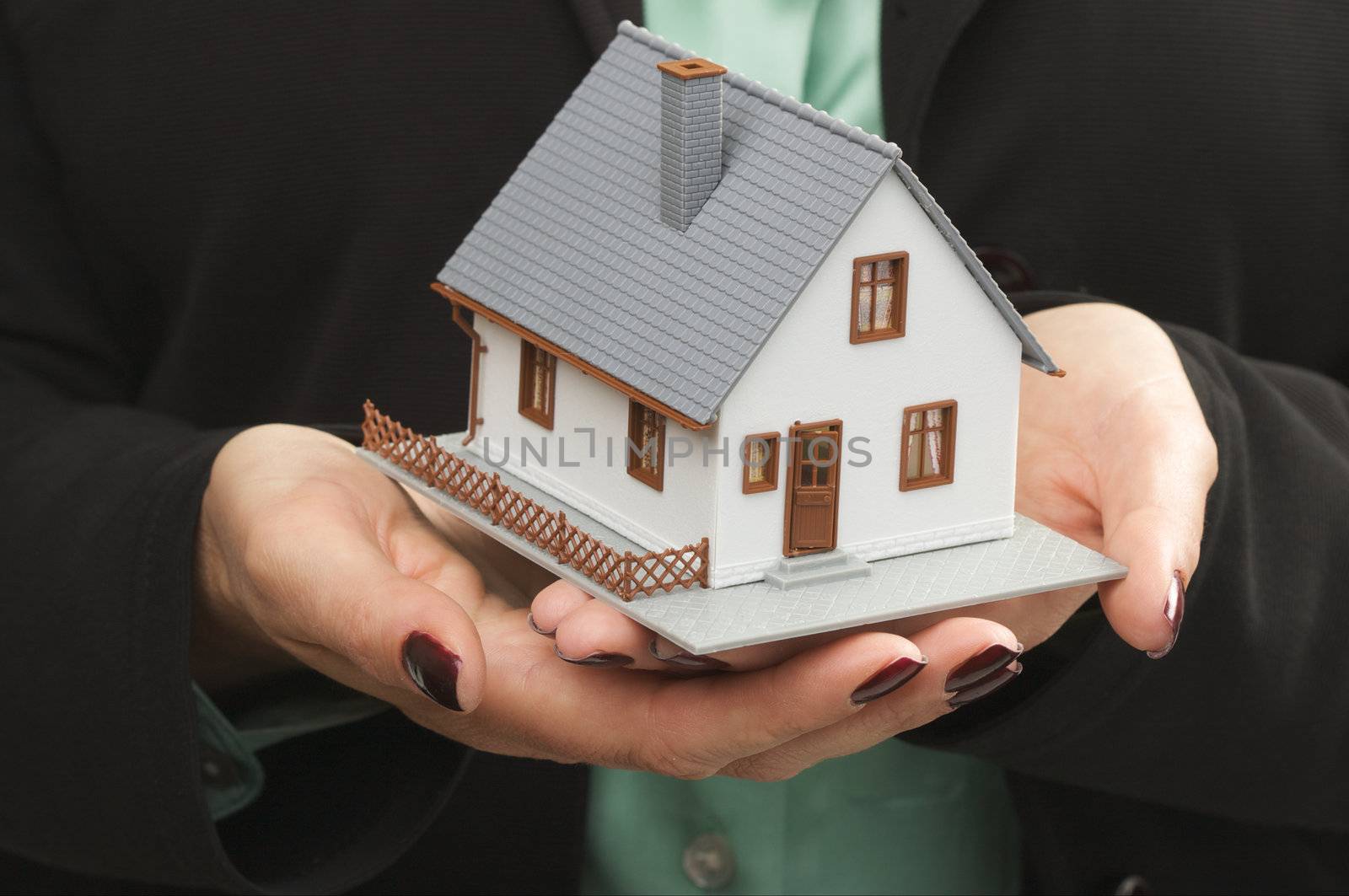 Female hands holding small house.