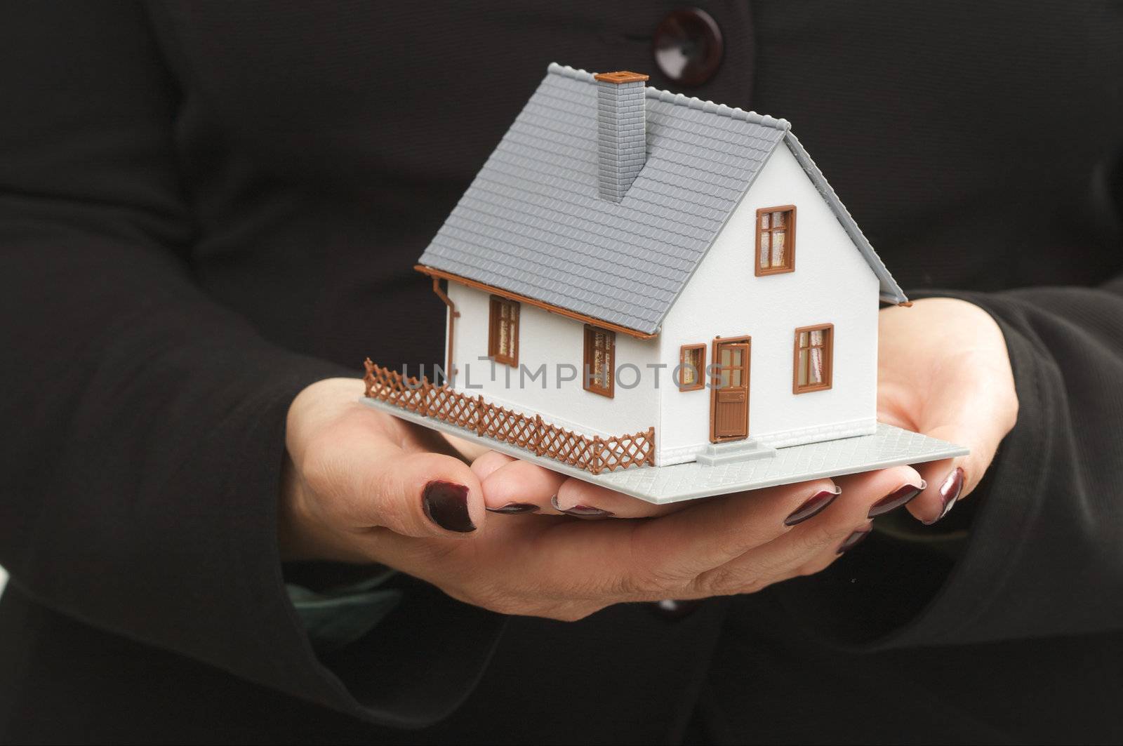 Female hands holding small house.