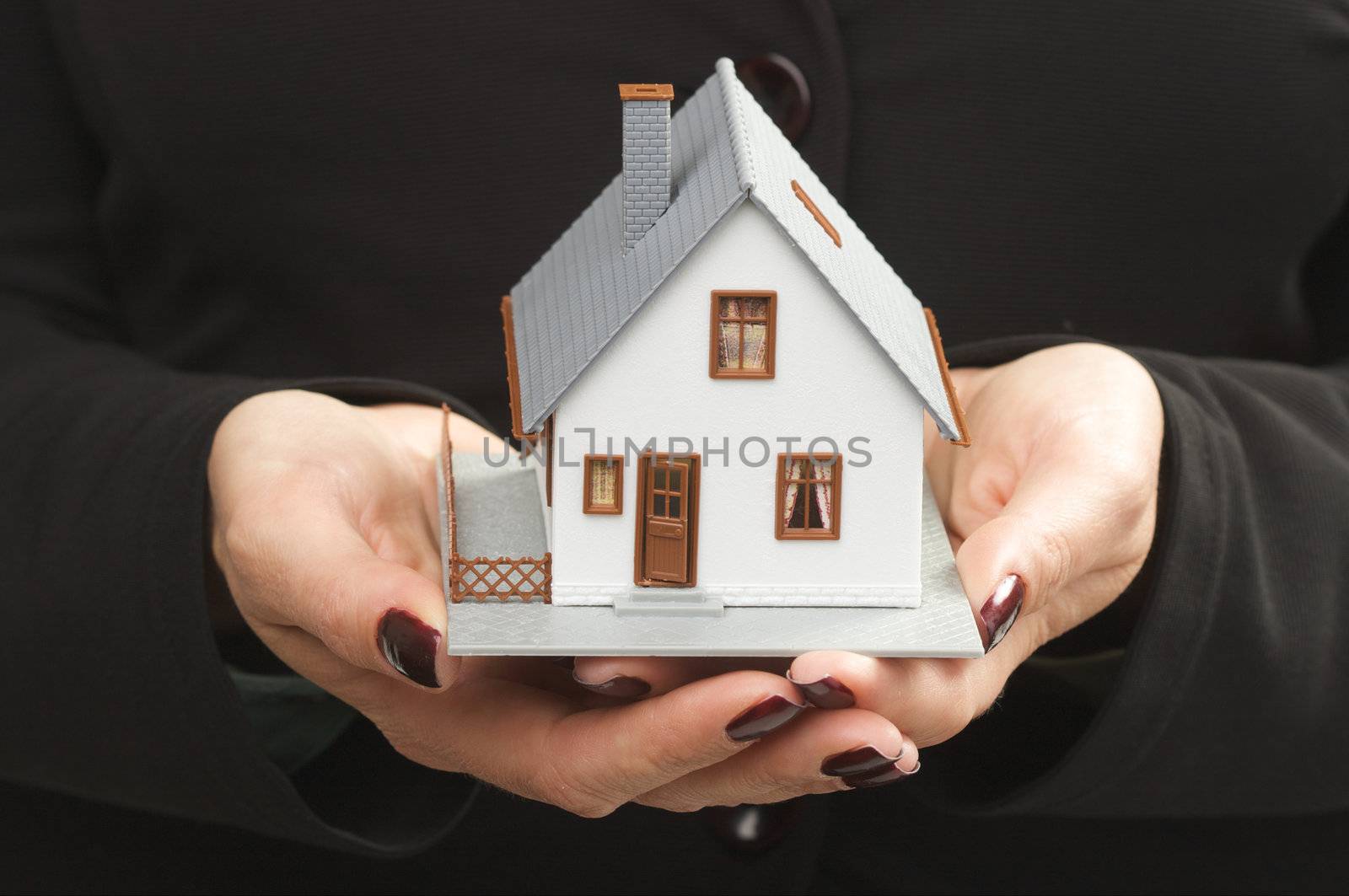Female hands holding small house.