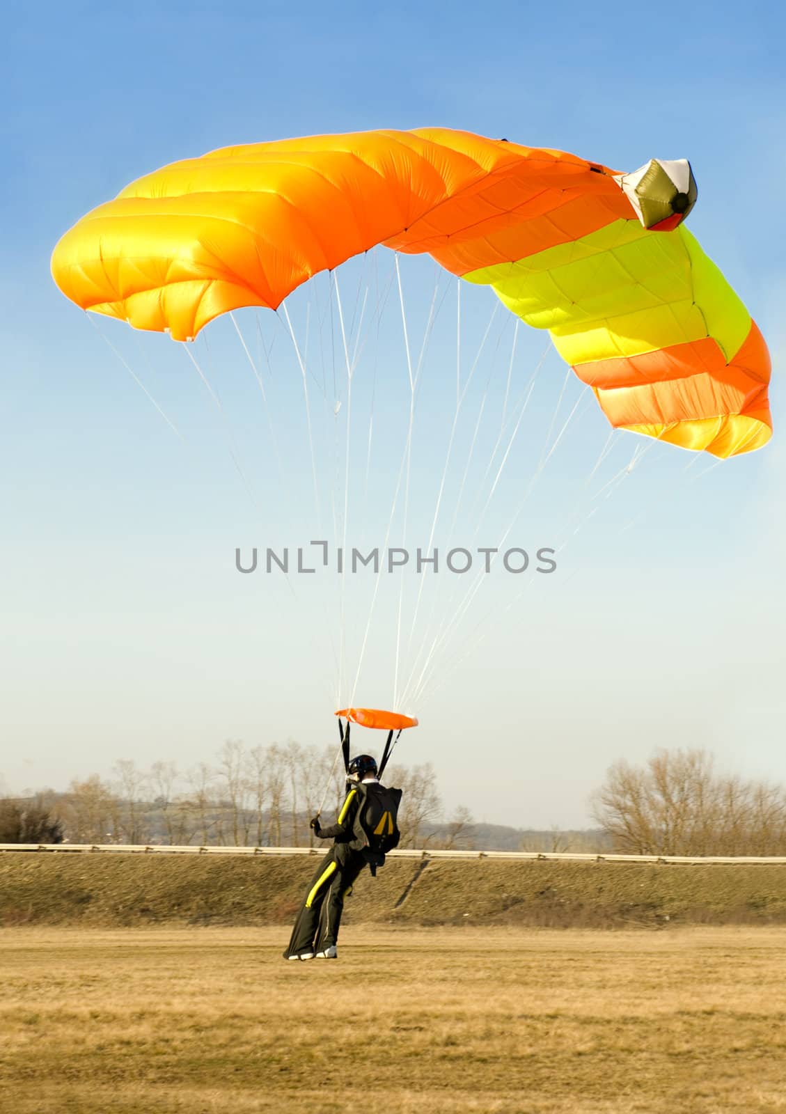 an orange parachute is landing softly on a sunny day