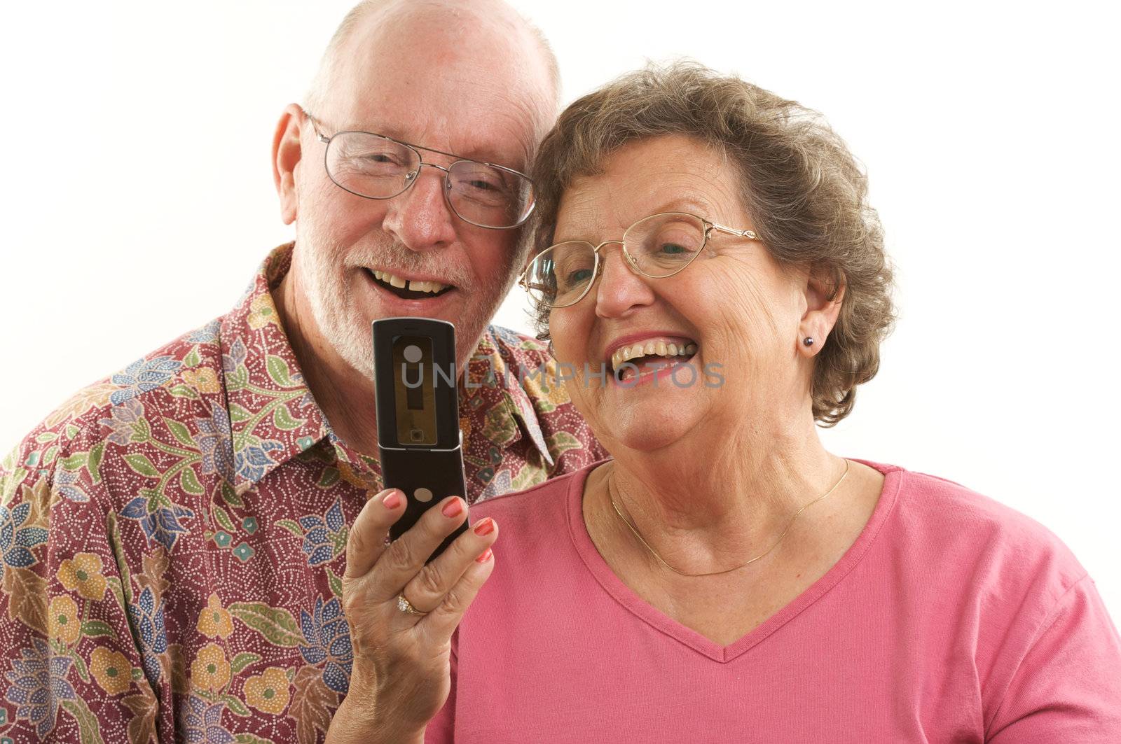 Senior Couple looks at the screen of a cell phone.