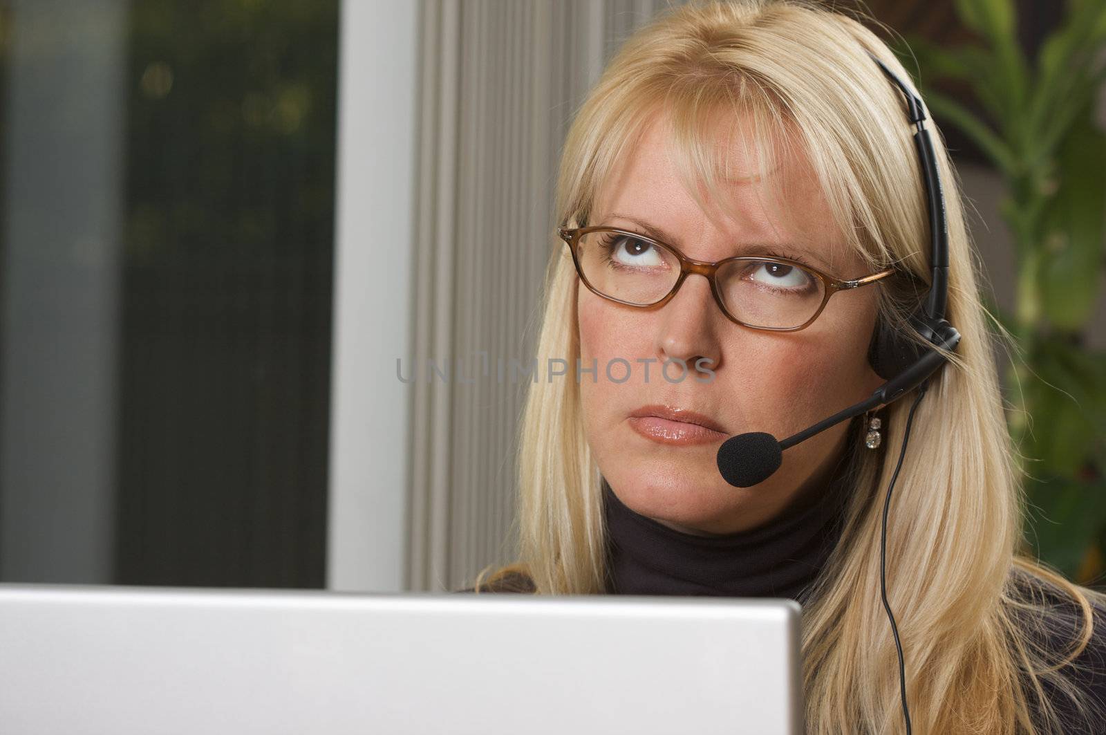 Attractive businesswoman shows signs of boredom while on her phone headset.